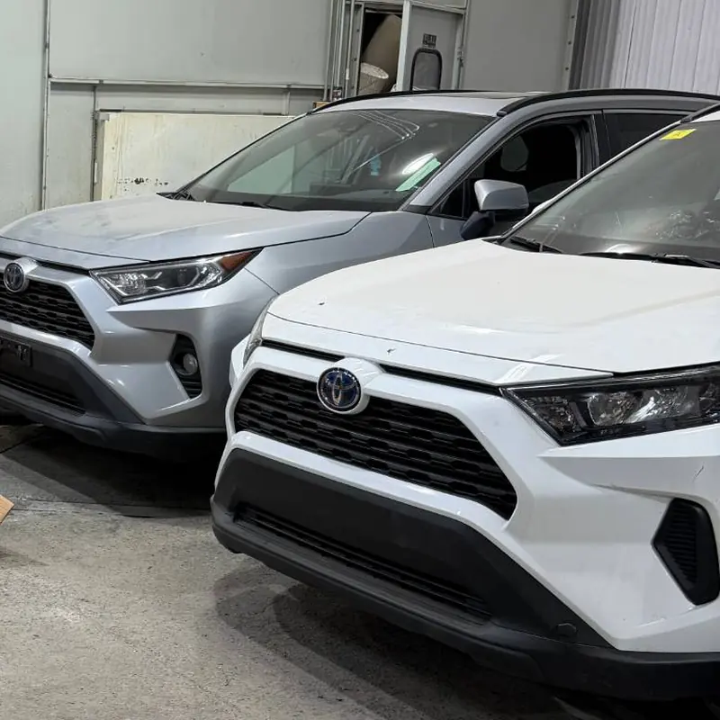 Two Toyota RAV4s, one silver and one white, parked inside the warehouse
